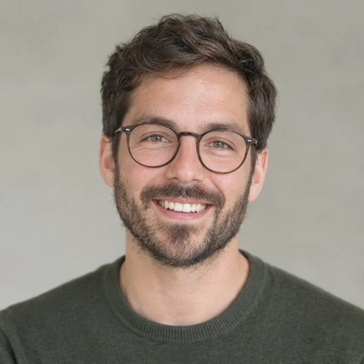 Photo of a smiling man with a short beard and round glasses